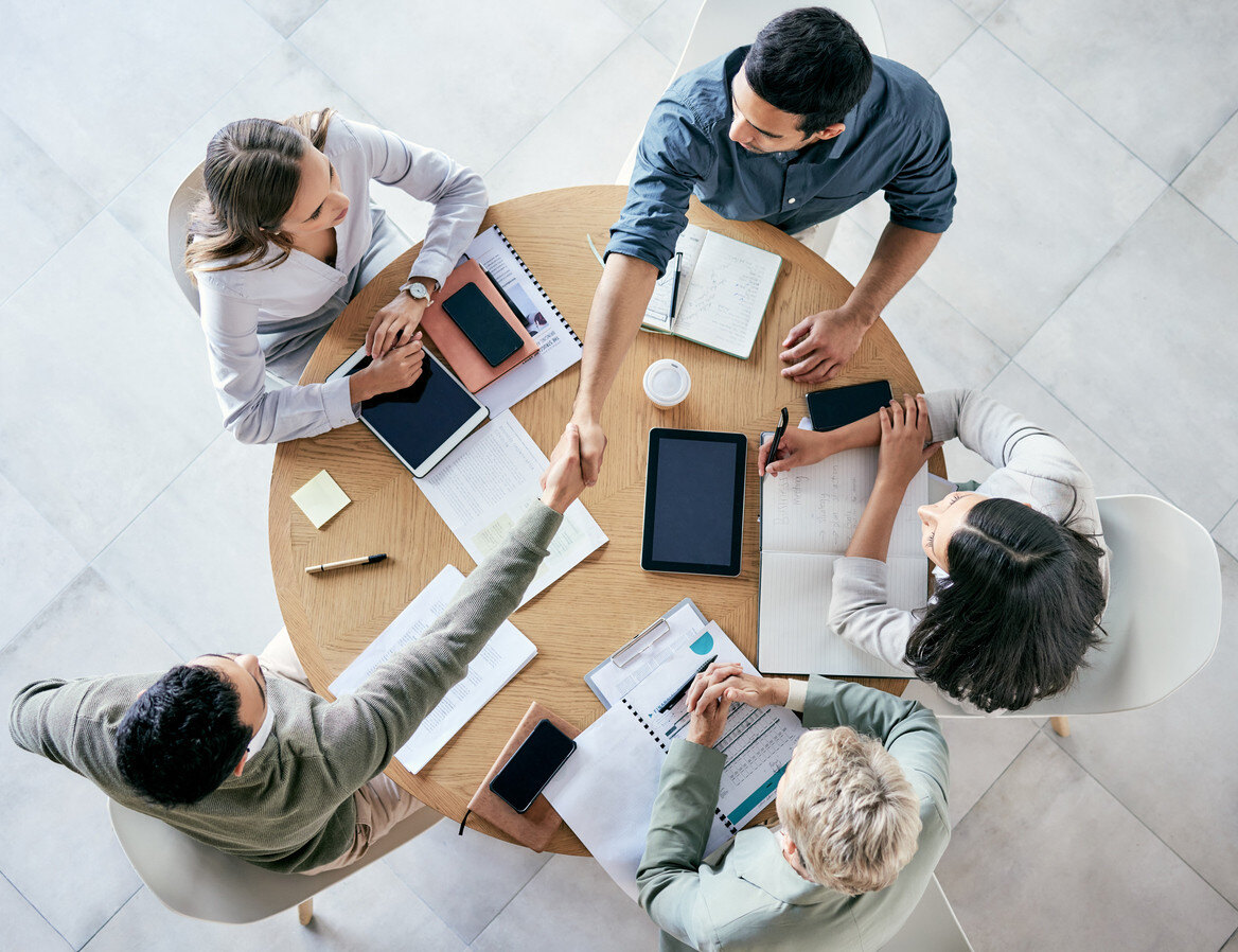 Employees shaking hands over a conference table