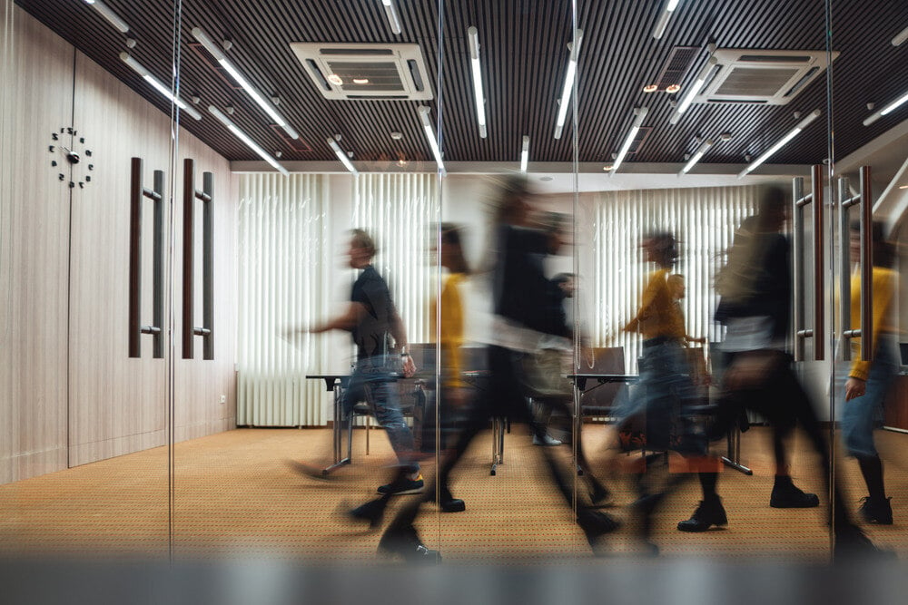 Busy office shows employees walking toward leadership development program