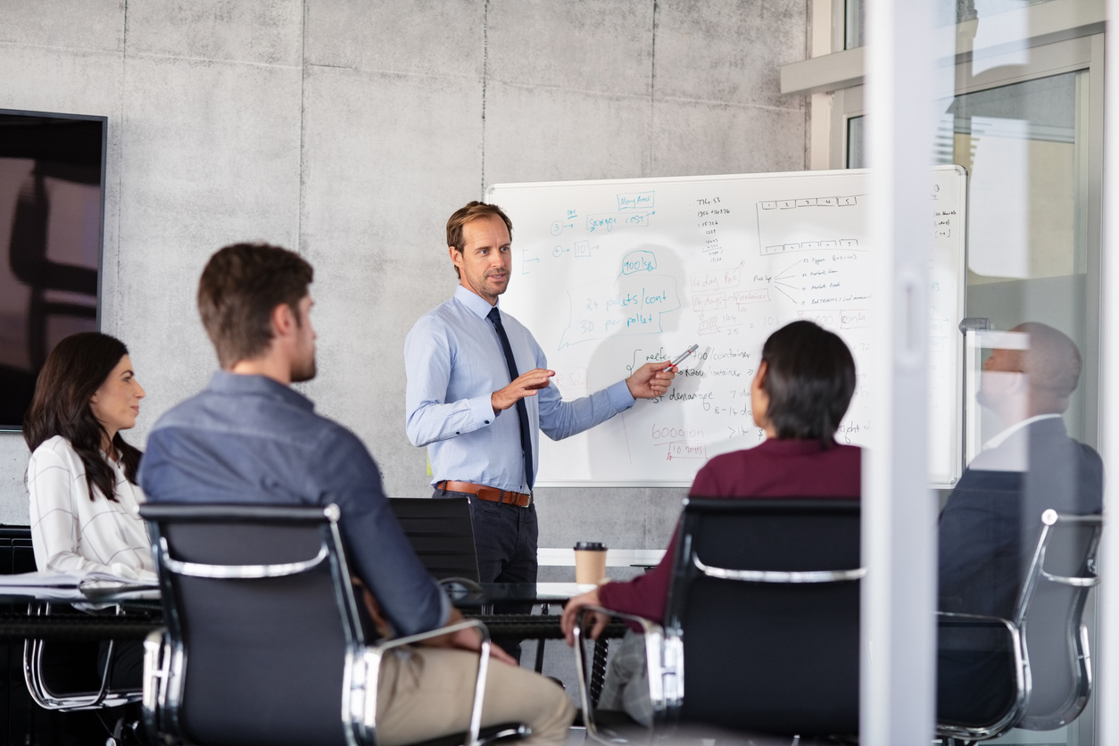 Leader giving presentation in front of white board